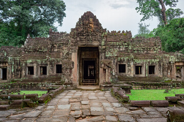 Moss covered green stone brick exterior design of the Preah Khan Temple entrance in the lush forest of Angkor Wat historical site Siem Reap Cambodia