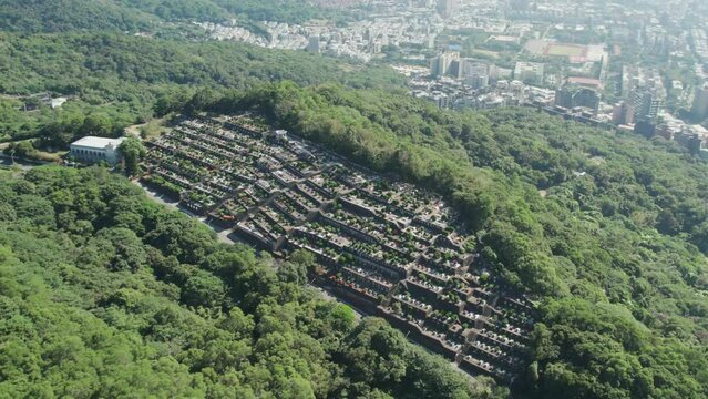 A traditional Taiwanese cemetery nestled in lush greenery with Taipei in the background, Aerial