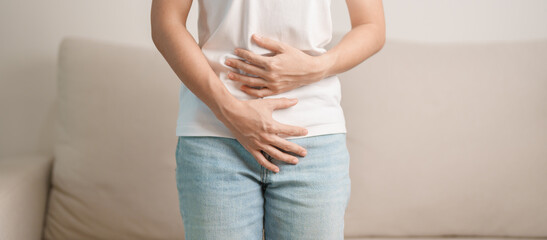 woman having abdomen ache due to Stomach pain, digestion with constipation or Diarrhea from food poisoning, female problem and Endometriosis, Hysterectomy and Menstrual on the sofa at home