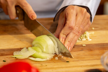 chef cortando cebola fresca na tábua de madeira preparando o tempero
