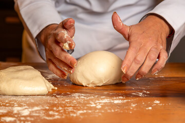 detalhe da mão do chef amassando massa fresca de pão na bancada de madeira