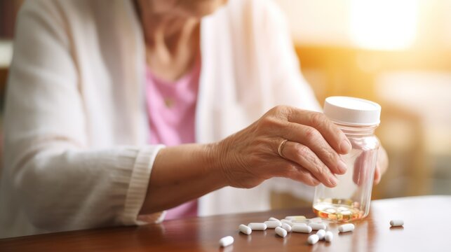 A Close up of Old woman closes pill bottle to take medicine, treat memory loss, high blood pressure or cholesterol level as painkiller, concept of treatment for diseases in old age