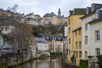 Fototapeta na wymiar Colorful pink, yellow, and grey buildings in the old town village along a canal river reflection of Luxembourg City Europe