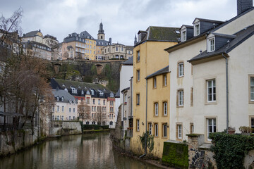 Fototapeta na wymiar Colorful pink, yellow, and grey buildings in the old town village along a canal river reflection of Luxembourg City Europe