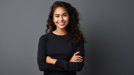 Portrait of young Mexican woman with pleasant smile and arms crossed isolated on gray wall with copy space Beautiful young woman with folded arms looking at camera against gray wall. isolated studio