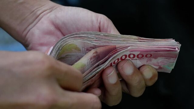 Counting a stack of hundred thousand rupiah notes. The concept of investment, exchange, salary, credit, deposits