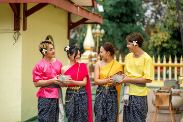 Songkran Festival - Young Asians Wearing Thai Clothes Pose Happily Playing in the Water During Songkran Festival, Buddha Statue Bathing Ceremony During Songkran Festival, Splashing water.