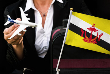 business woman holds toy plane travel bag and flag of Brunei