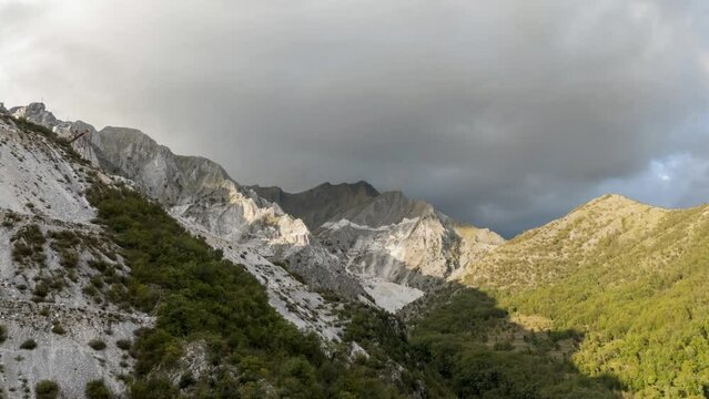 Majestic mountain range in Tuscany with sunlit peaks and looming clouds, aerial hyperlapse