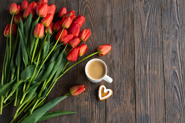 Fresh orange tulips and cappuccino mug with spring composition. Greeting card with copy space for Valentine's Day, Woman's Day and Mother's Day.