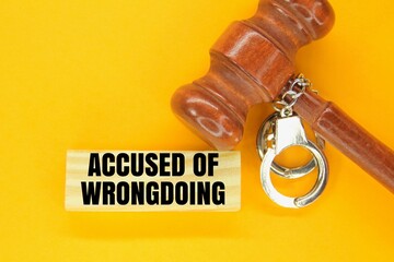 judge's hammer, iron handcuffs and sticks with the words accused of wrongdoing. the concept of...