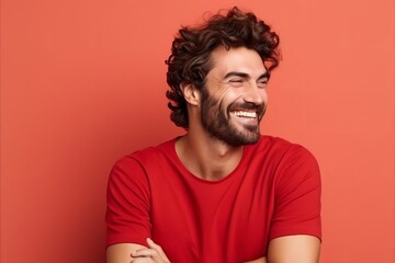 Portrait of a handsome young man laughing and looking away against red background