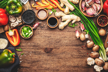 Obraz na płótnie Canvas Vegan food and cooking background. Wooden table with vegetables, spices and ingredients for preparing vegetarian Asian dishes with mushrooms and soy sauce. top view, copy space