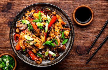 Stir fry turkey slices with red paprika, mushrooms, chives and sesame seeds with ginger, garlic and soy sauce. Old wooden table background, top view