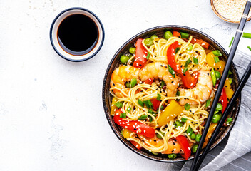 Spicy stir fry noodles with shrimps, colorful paprika, green pea, green onion and sesame seeds with...