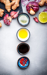Food and cooking background. Gray table with spices and ingredients for cooking Asian dishes with ginger, garlic, soy sauce and lime, top view