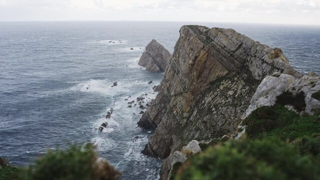 Scenic seascape in Cabo Pe&ntilde;as cliffs in Asturias Spain, ocean water crashing against rock formations beach coastline 