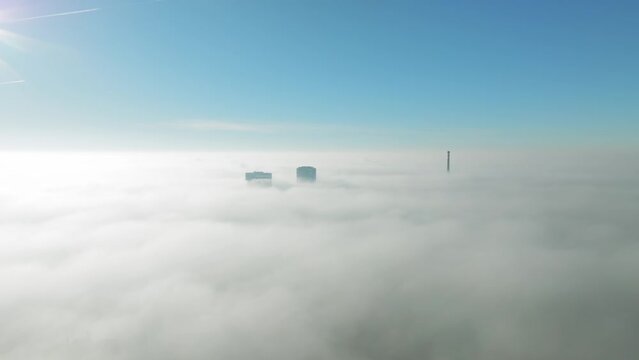 Sunlit aerial winter cloud journey: Drone moves forward towards towering skyscrapers piercing through inversion clouds revealing city views. Cinematic beauty of urban exploration. LuPa Creative.
