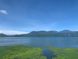Lago, cielo azul, y montañas de fondo