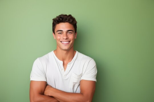 Portrait of a handsome young man smiling and looking at camera against green background
