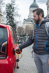 man charging an electric car on the street