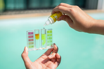 Action of person hand is using water tester kit with chemical to measuring Chlorine concentration of the swimming pool (as blurred background). - obrazy, fototapety, plakaty