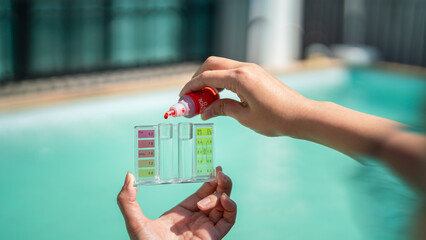 Action of a person hand is using Phenol red droplet to drop into sample water for measuring the pH...