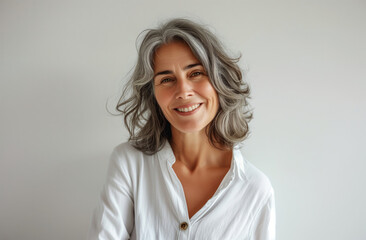 Obraz premium Effortless Elegance: Radiant Woman with Silver Waves and Playful Smile in White