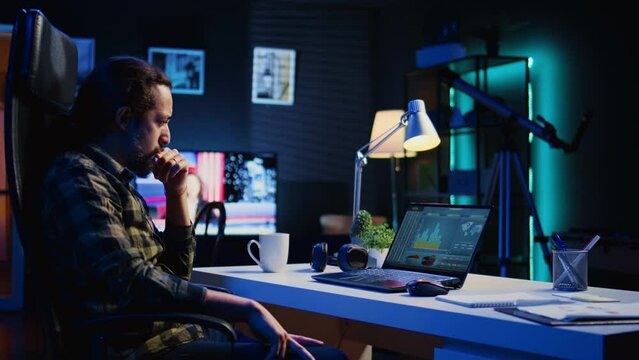 Remotely working company financial advisor analyzing statistical graphs on laptop screen at home. Freelancer using electronic device to compare business revenue numbers in apartment office, camera B