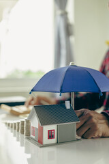 Holding hands holding an umbrella on the house Home insurance concept and family protection,...