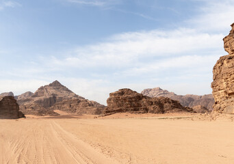 Fototapeta na wymiar Tread marks from the off road vehicle tires in the red desert surrounded by the high mountains in the the Wadi Rum desert near Amman in Jordan