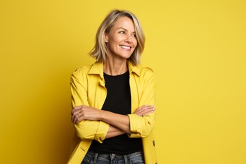 Portrait of a happy mature woman in yellow jacket over yellow background