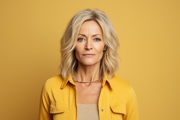 Portrait of mature woman looking at camera, isolated on yellow background