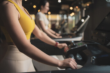 Two young woman are jogging on treadmill during her sports training in a gym. - obrazy, fototapety, plakaty