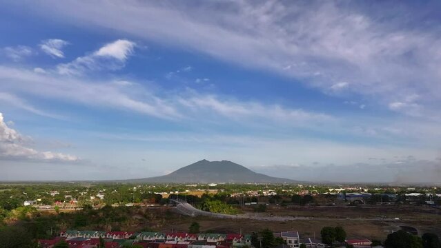 Giant Arayat Volcano on Philippines during blue sky with clouds. Traffic on highway. View from suburb neighborhood in San Fernando. Aerial backwards shot.