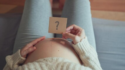 Concept of choosing baby name, Pregnant woman holding paper with question mark.