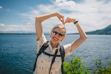 Woman smiling with arms in a heart shape at Jenny Lake in Grand Teton National Park