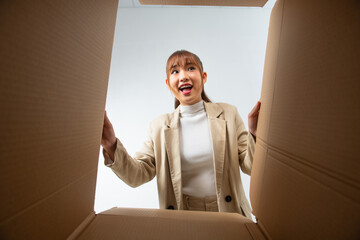 smiling female surprised unpacking christmas gift big box and looking inside, inside bottom view