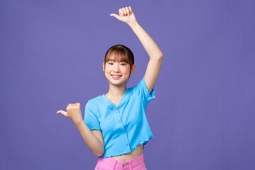 Young asian woman smiling with happy face looking and pointing to side with thumbs up.
