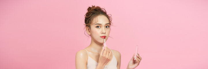 Young woman applies lipstick on lips - obrazy, fototapety, plakaty