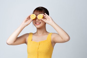 sensual woman covering eyes with half of lemon isolated on white