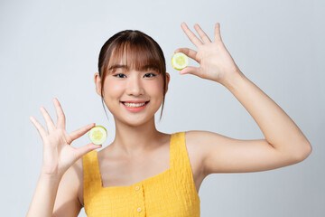 A gorgeous young woman holding cucumber slices while isolated on white background.