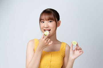 A picture of a face of a beautiful woman posing with a cucumber over white background