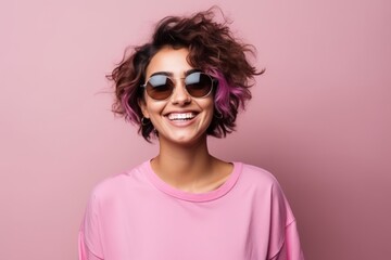 Portrait of a beautiful smiling young woman in sunglasses over pink background