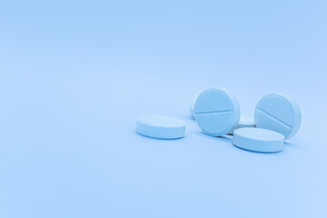 Blue pills isolated on a blue background. Focus on the foreground, soft blur the background. Close-up. Theme is treatment of diseases, medicine and pharmaceuticals.