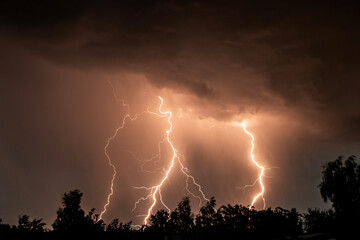 beautiful lightning during a thunderstorm at night in a forest that caused a fire, against a dark...