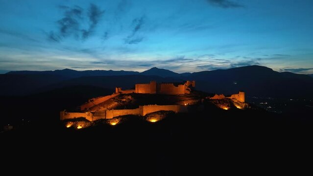 Aerial footage of an illuminated castle on top of the hill at dusk
