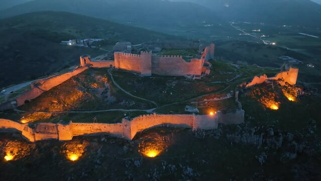 Drone footage over an illuminated medieval castle at dusk