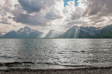 Dramatic sunbeams, clouds, and snowcapped mountains over Jackson Lake in Grand Teton National Park