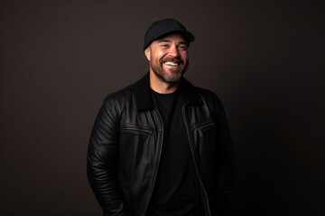 Handsome man wearing a black leather jacket and cap on a dark background